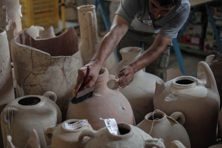 Specialist in the restoration and maintenance of antiquities works on cleaning the antiquities inside a warehouse for the outputs of the archaeological excavation in Gaza City