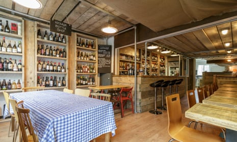 Corkage in Bath, with a tablecloth on one table, high stools at the bar and wine bottles on shelves in the wall