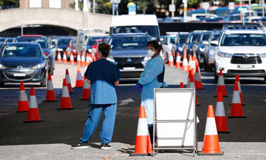 A Covid testing clinic in Sydney. Healthcare workers wait for the next vehicle at a drive-through testing site.