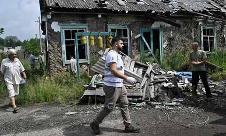 A volunteer medic walks past a destroyed building in the Donetsk village of Staryi Karavan on Friday