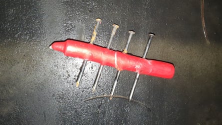 A red candle with four nailed hammered through it