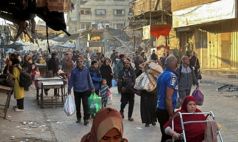 People carry their possessions through a partially destroyed street