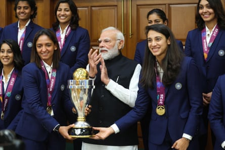 Narendra Modi with two members of the team holding the cup and other players standing behind them