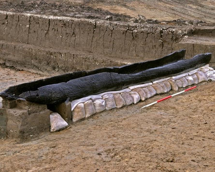 A log boat sitting on top of sand bags.