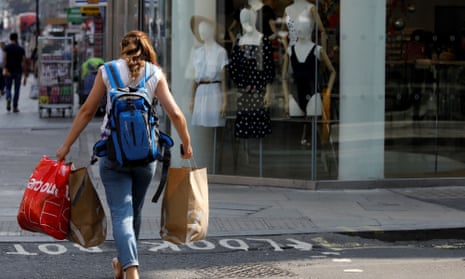 young woman carrying shopping bags next to clothes shop