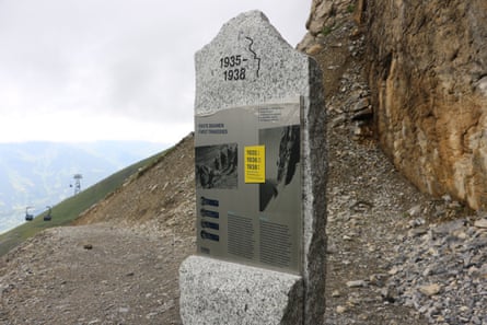 A slab of rock showing information on a mountain side with a ski lift in the background