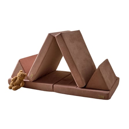 A foam play sofa set forms a triangular tent shape with scattered cushions and a teddy bear