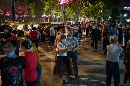 Couples wearing face masks dance in a park next to the Yangtze River in Wuhan on 12 May