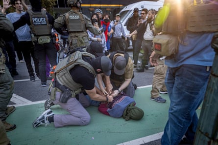 three masked men arrest a person lying on the ground