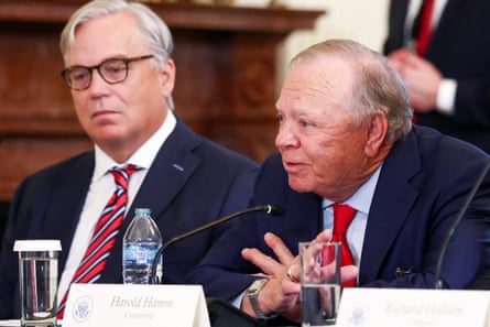 a man speaks into a microphone while seated next to another man at a table