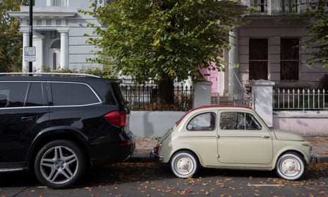 An SUV dwarfs a tiny Fiat 500 on a London street.