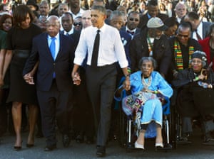 John Lewis and Amelia Boynton Robinson (in wheelchair), hold hands with Barack Obama and Michelle Obama on the 50th anniversary of the Bloody Sunday march across the Edmund Pettus Bridge in Alabama, 2015. Both Lewis and Boynton Robinson were badly beaten that day.
