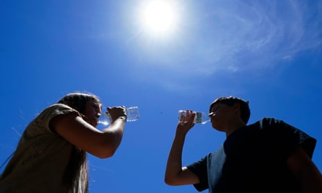 Teenagers drink water in the heat in Phoenix. Dozens of cities have had streaks of days with temperatures at 90F and above.
