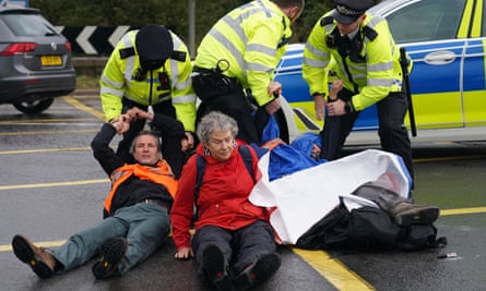 Police officers detain protesters blocking the M25 near Heathrow on Monday.