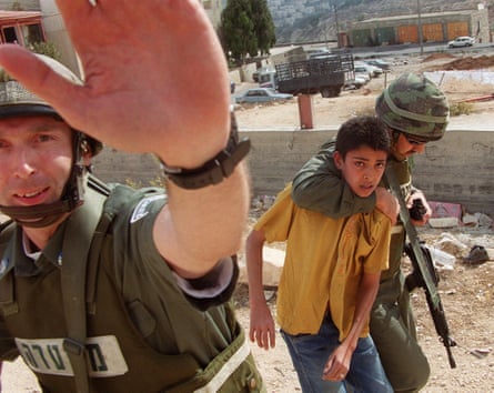 Los guardias fronterizos israelíes arrestan a un niño palestino durante un enfrentamiento de lanzamiento de piedras en el campo de refugiados árabe de Shawfat en Jerusalén oriental en 2000.
