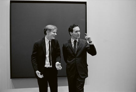 Andy Warhol and fellow pop artist Robert Indiana talk in front of a canvas by Ad Reinhardt at the opening of the exhibition Americans 1963 at MoMA
