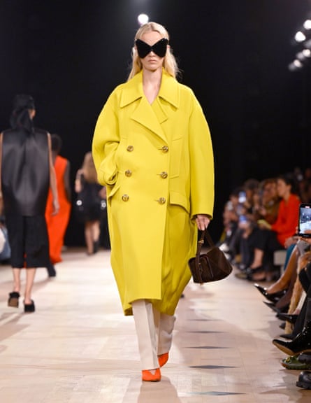 Woman wearing a yellow ‘cocoon’ coat and large wraparound sunglasses