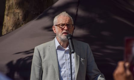 Jeremy Corbyn, in a shirt and suit jacket, and wearing glasses, speaks into a microphone in the sun