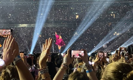Fans try to film Taylor Swift on their phones as she performs on stage at Wembley Stadium in London