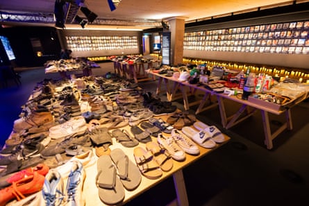 Room from exhibition including table of shoes with other belongings around