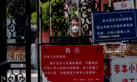 A man on quarantine stands behind the fence looking at a street during the city lockdown in Shanghai, China, 25 April 2022. 