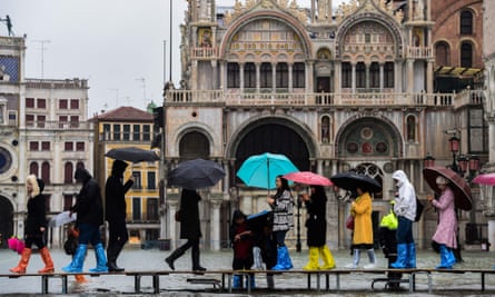 Tourists walk across a footbridge on the flooded St Mark’s Square in Venice.