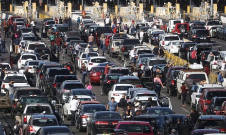People attempting to cross into the US look on by their vehicles during a temporary closure of the San Ysidro port of entry stands closed at the US-Mexico border on 25 November 2018 in Tijuana, Mexico.