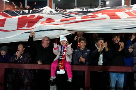 Οι οπαδοί του Fleetwood Town ζητωκραυγάζουν και χειροκροτούν κάτω από ένα μεγάλο πανό στην εξέδρα του σταδίου