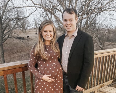A blonde female successful a brownish polka dot dress holds her babe bump opinionated adjacent to a brownish haired man successful jeans, a garment and a blazer.