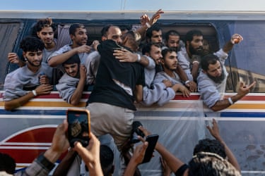 Palestinian detainees hang from the window of a vehicle