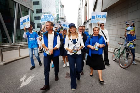 Ebba Busch walking down a street with other politicians and volunteers waving placards
