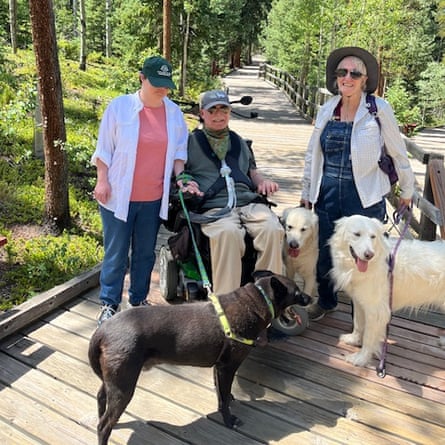 Three people, 1 successful a wheelchair, and 3 dogs