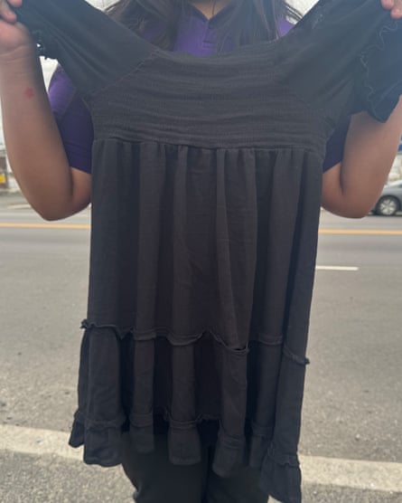 A person holds a modest black dress.
