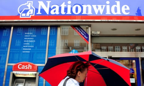A woman holding an umbrella walks past a Nationwide branch