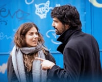 A couple in front of a blue wall with graffiti