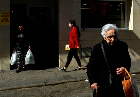 A woman wearing a surgical mask arrives to do the shopping at a supermarket at the Usera neighbourhood in Madrid