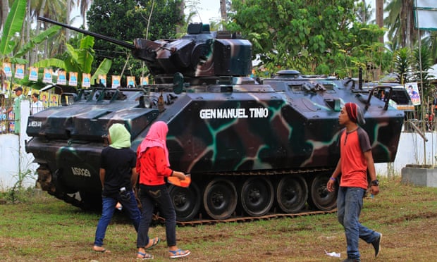 Residents walk past a tank outside a polling station in the town of Pantar, in Mindanao, on 9 May as people vote in the Philippines’ presidential election. 