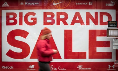 Shopper in front of 'big brand sale' sign in window