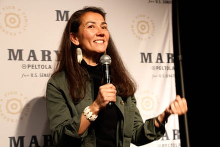 A woman speaks in to a microphone and smiles.