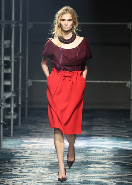 Model on the catwalk weraing mid-length tomato skirt and a plum top