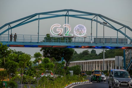 Traffic moves past an illuminated G20 logo installed on pedestrian bridge outside the main venue.