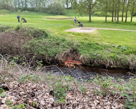 Men tending to the greens at a golf course with a contaminated waterway in the foreground