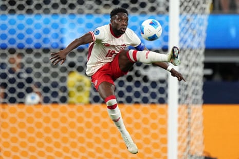 Alphonso Davies of Canada in the air kicking a ball with his raised left foot