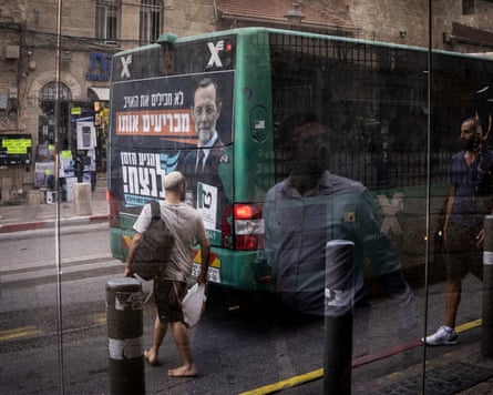 People walk past a bus with an election campaign banner for Moshe Feiglin of the Zehut party in Jerusalem.