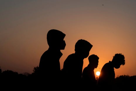 Silhouette of four minors walking at sunset.