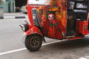 A tuk painted red with a picture of Joaquin Phoenix’s version of the Joker painted on the front
