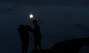A couple take a picture of the supermoon rising over Ischigualasto provincial park