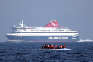 migrant boat passes a passenger ferry as it makes the crossing from Turkey to the Greek island of Lesbos