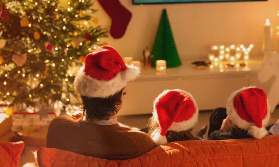 A family in Santa hats watching Christmas television
