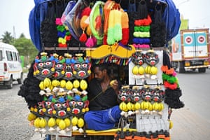 A man sitting inside his small stall covered in masks